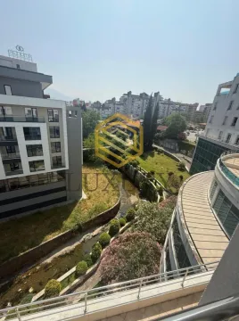 Pogled sa terase na gradsko okruženje i zelenu površinu sa potokom. - image 11
