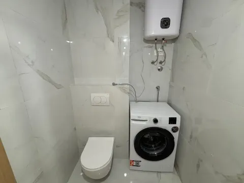 Smaller bathroom with a toilet, washing machine, and water heater. - image 10