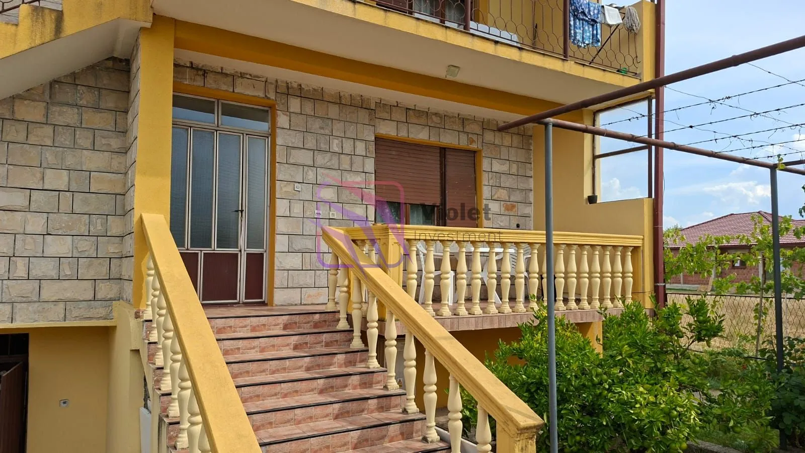 Exterior view of the house with stairs and a terrace.