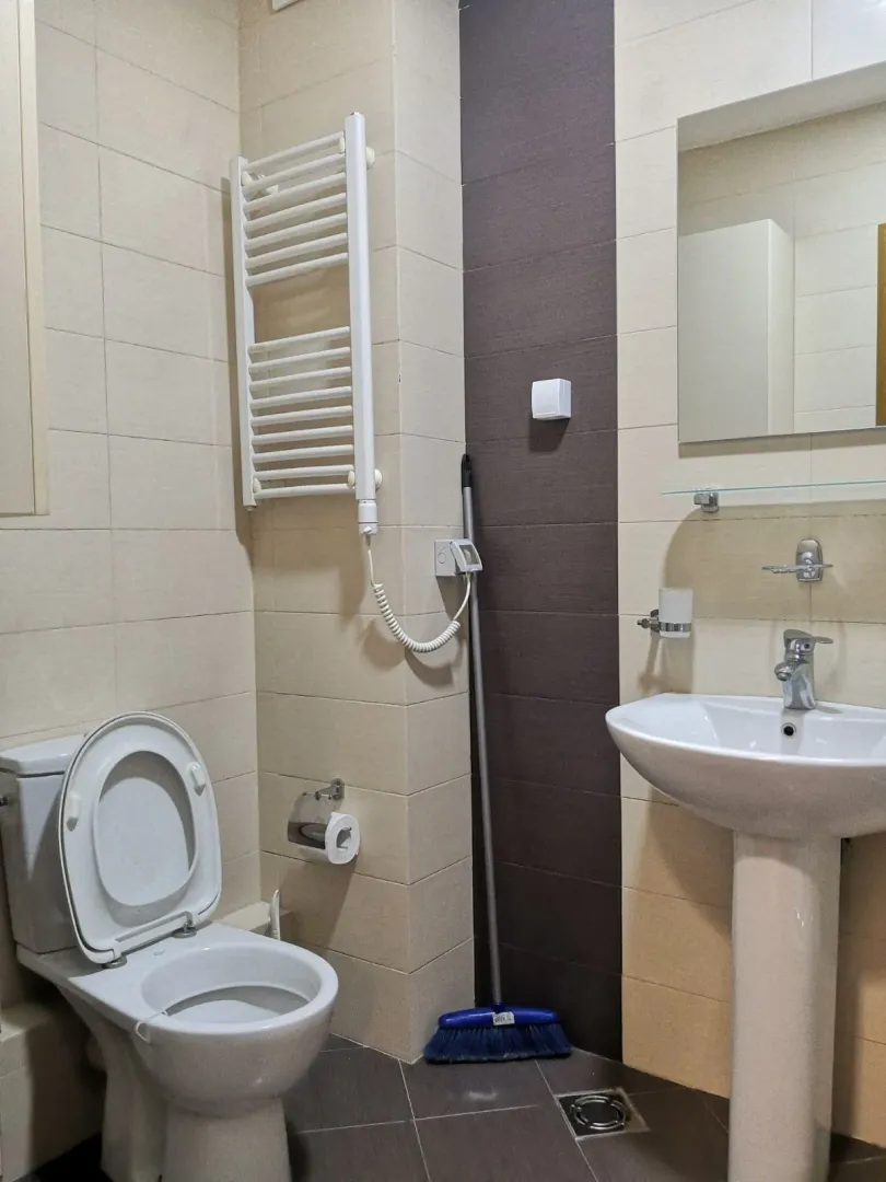 Jednostavno kupatilo sa lavaboom, toaletom i sušačem za peškire.