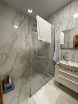 Bright bathroom with a glass shower cabin and marble-patterned tiles. - image 8