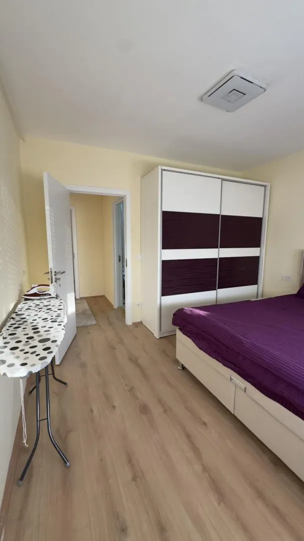 Spavaća soba sa bračnim krevetom, garderoberom i daskom za peglanje.