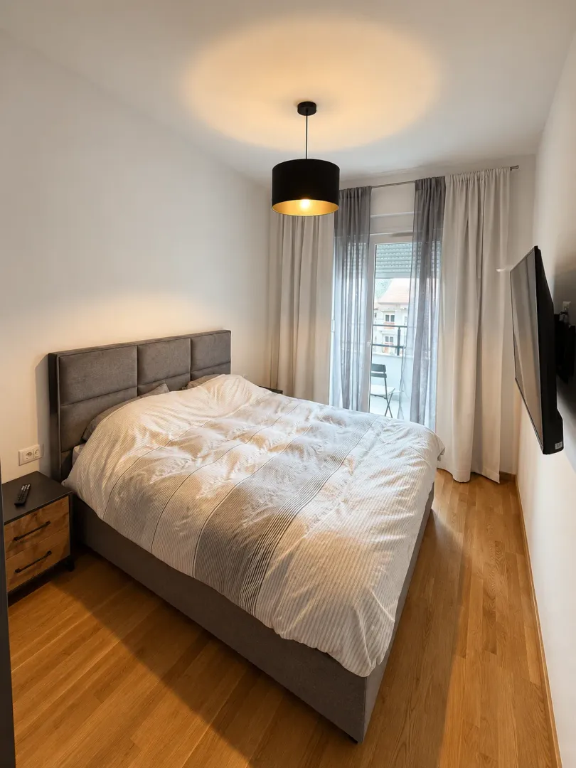 Bedroom with a double bed, wooden floor and access to the terrace.