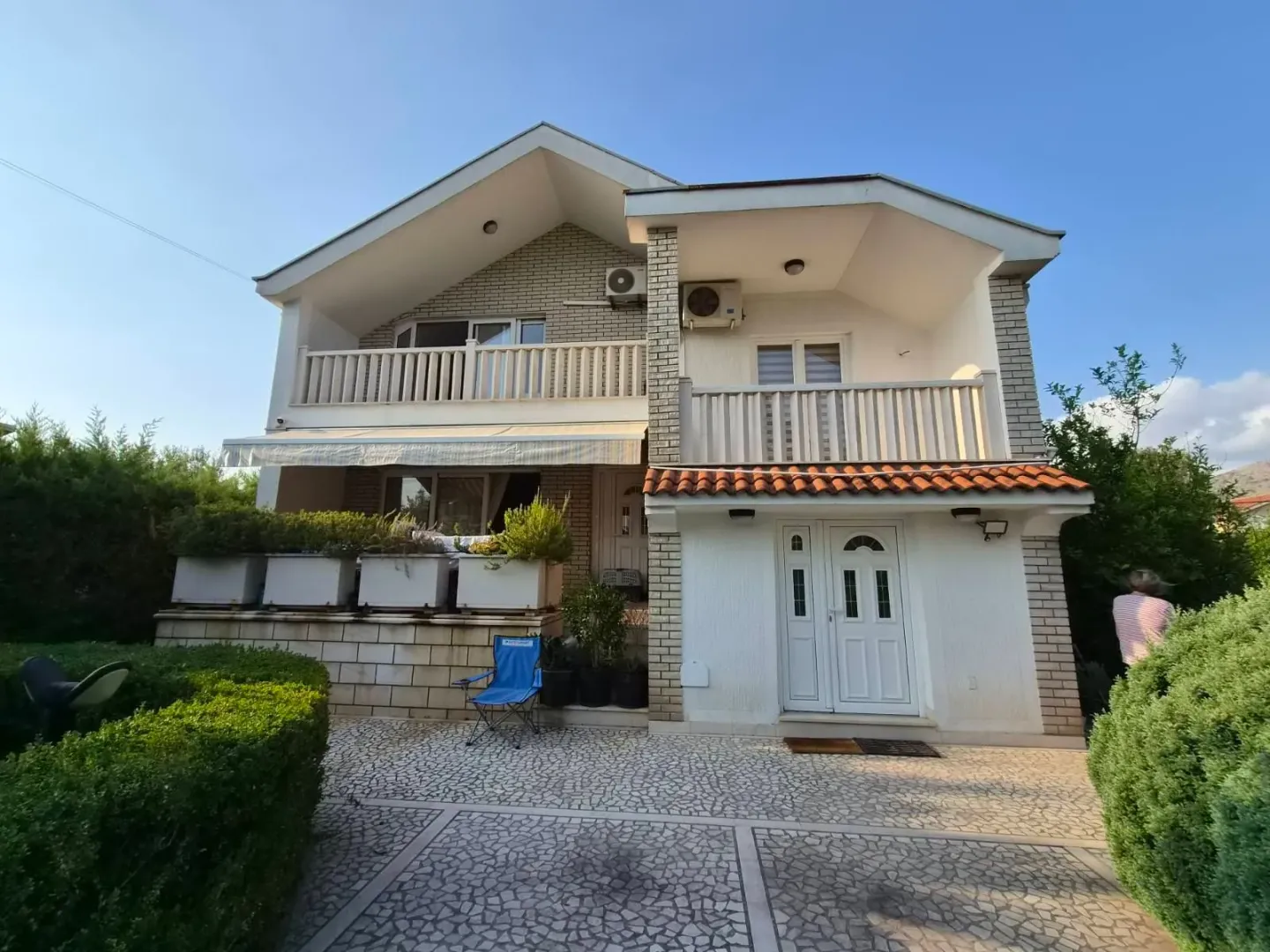 Exterior of a two-story house with a landscaped yard and terraces.
