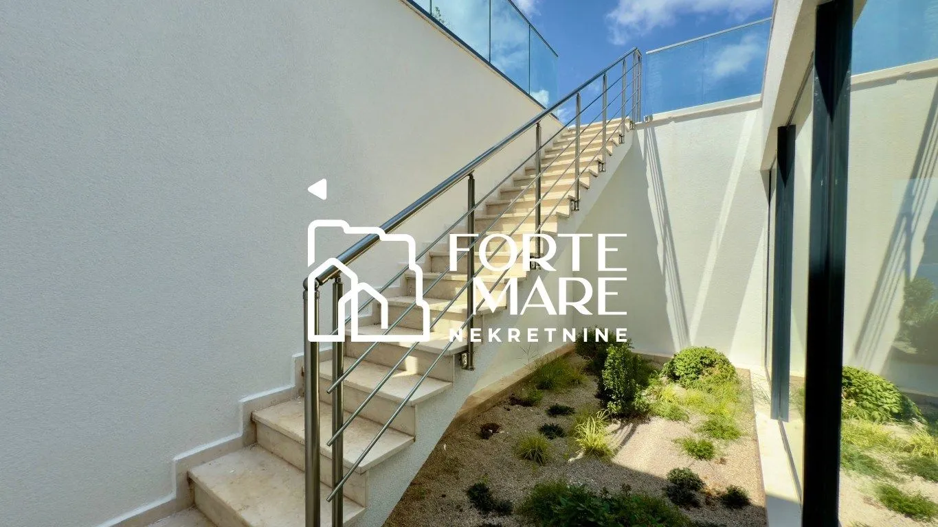 External stairs with a metal railing and a small landscaped courtyard.