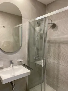 Modern bathroom with a sink, mirror, and shower enclosure. - image 4