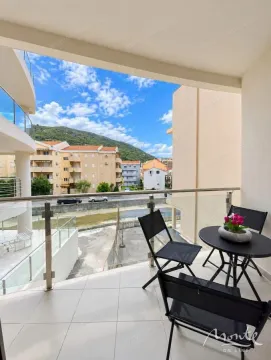 Natkriveni balkon sa garniturom za sjedenje i pogledom na okolne zgrade i brda. - image 10