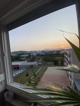 Pogled kroz prozor na grad i okolna brda pri zalasku sunca. - image 11