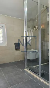 Bathroom with a shower cabin, toilet, and a window. - image 7