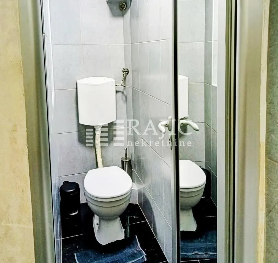 Small bathroom with a toilet and wall tiles.