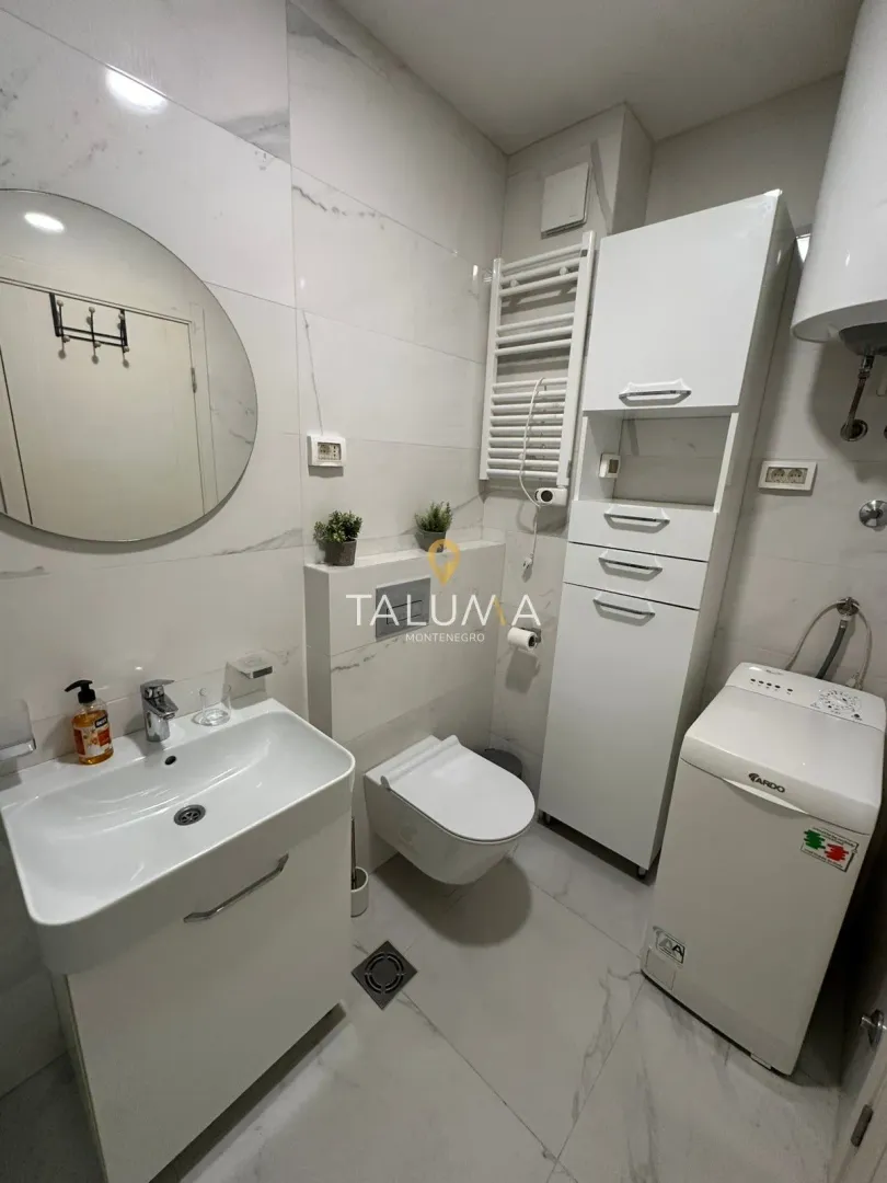 Moderne kupatilo sa umivaonikom, WC šoljom, ormarićem i mašinom za veš.