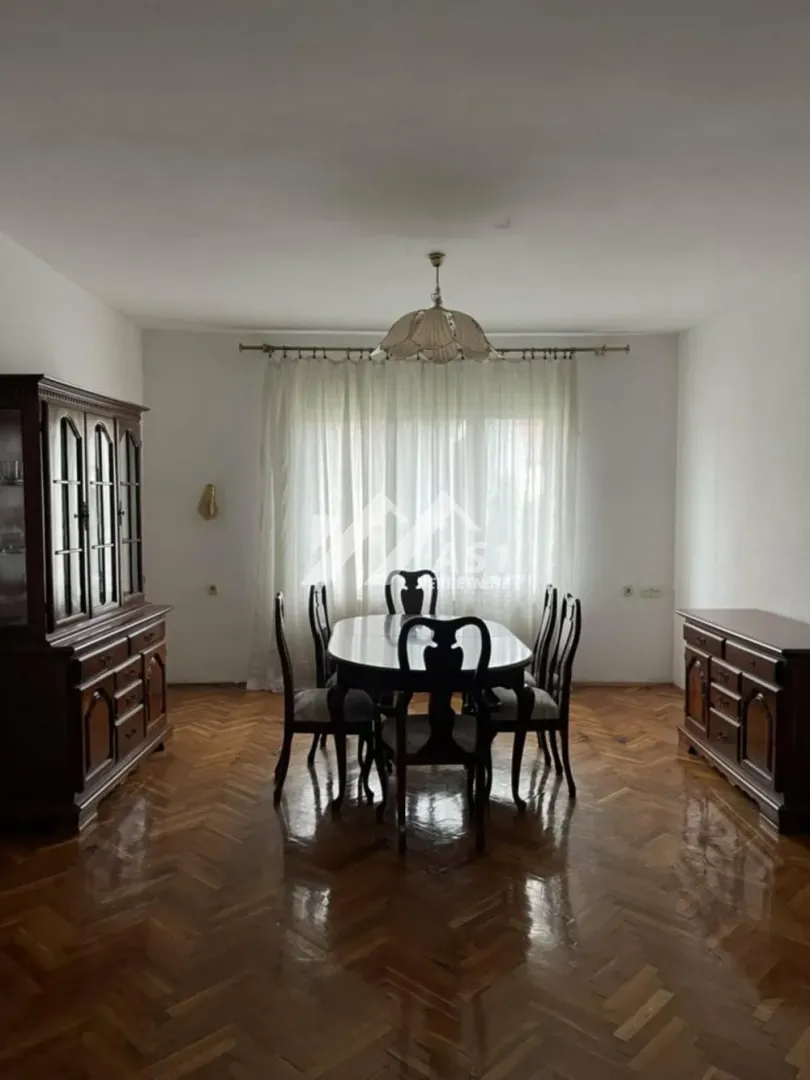 Trpezarija sa drvenim stolom, stolicama i komodama.