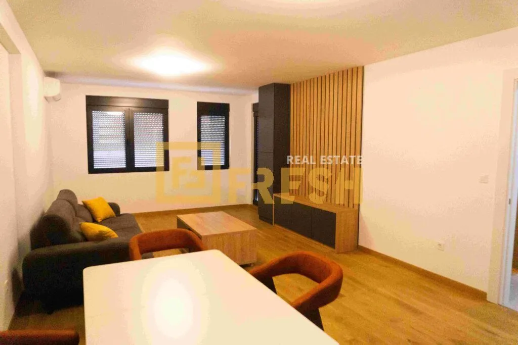 Living room with a sofa, dining table, and wooden wall panel.