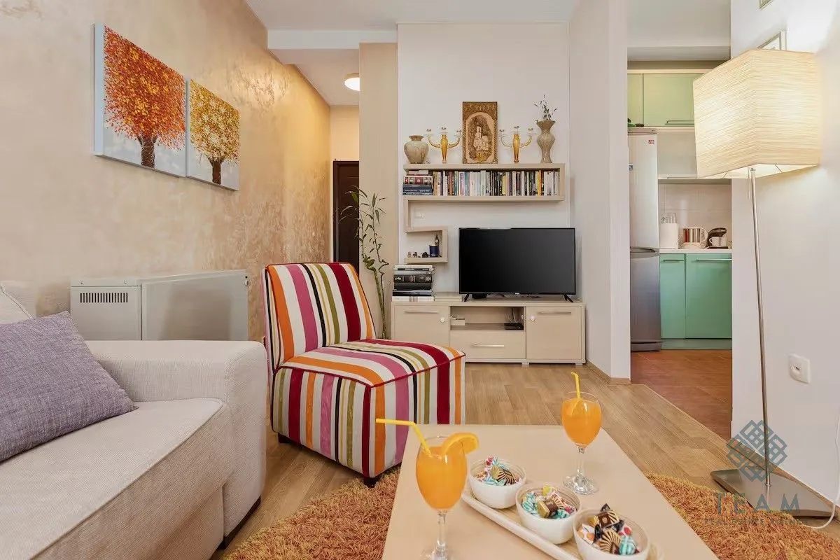 Living room with sofa, TV unit, and a view of the kitchen.