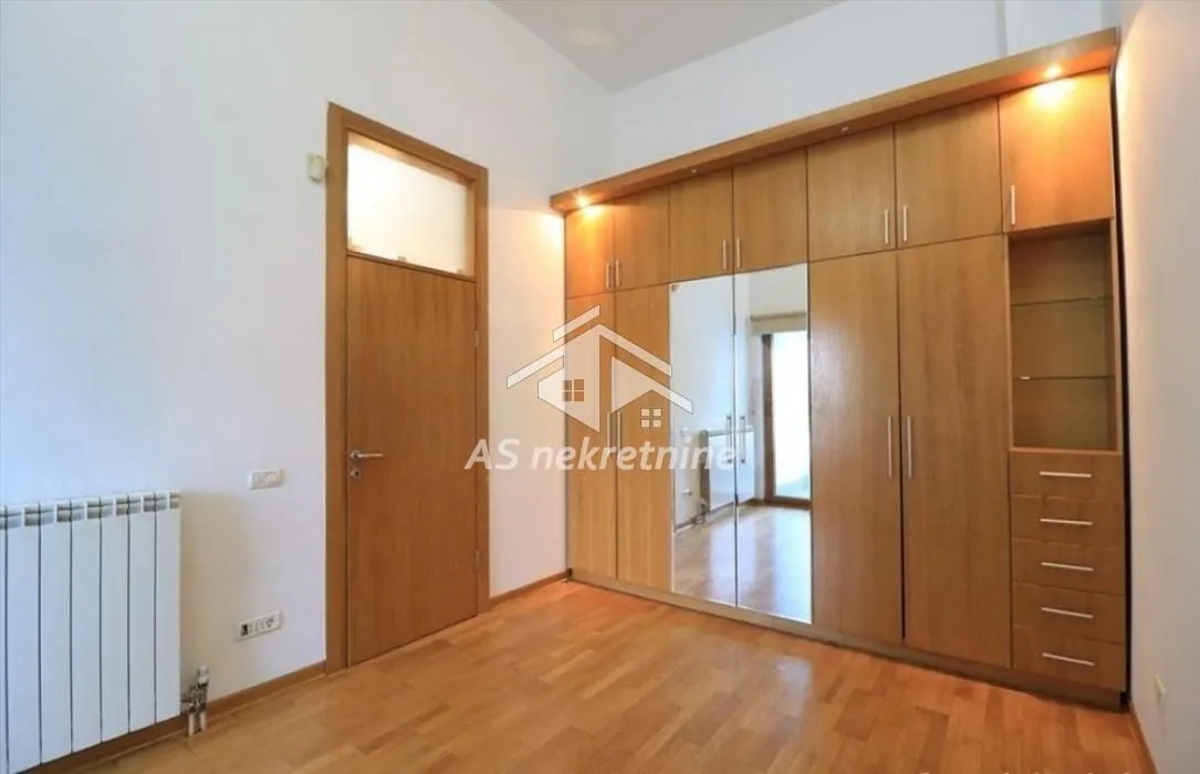 Bedroom with a large wooden wardrobe and parquet flooring.