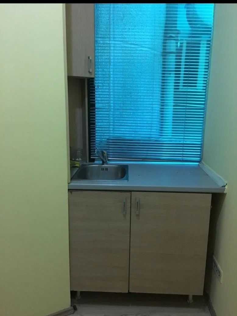 Small kitchenette with a sink next to a window.