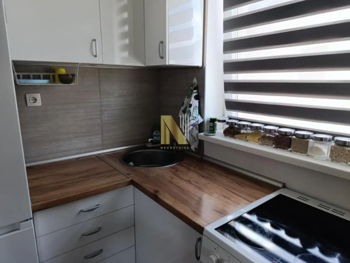Small kitchen with white cabinets, wooden countertop and a window.