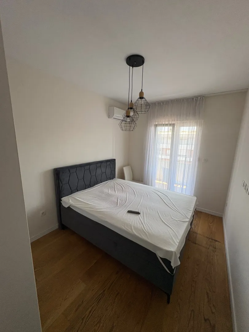 Bedroom with a double bed, wooden floor, and balcony door.