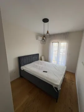 Bedroom with a double bed, wooden floor, and balcony door. - image 2