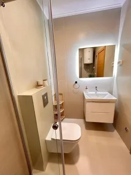 Modern bathroom with a wall-mounted toilet, sink, and backlit mirror. - image 8