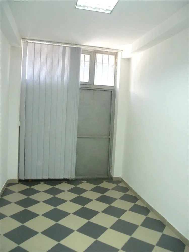 An empty room with checkered flooring and white walls.