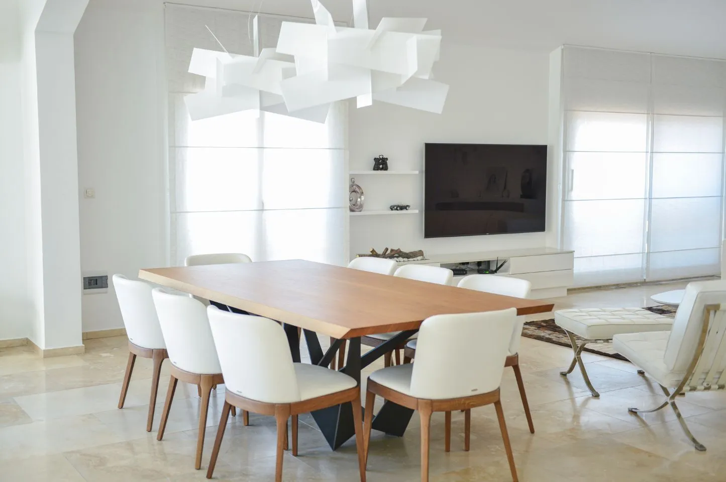 Dnevna soba sa trpezarijskim stolom i modernim lusterom.