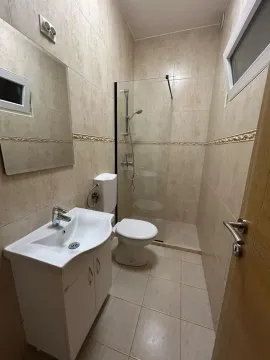 Small bathroom with a walk-in shower, washbasin, and toilet, tiled with ceramic tiles. - image 7