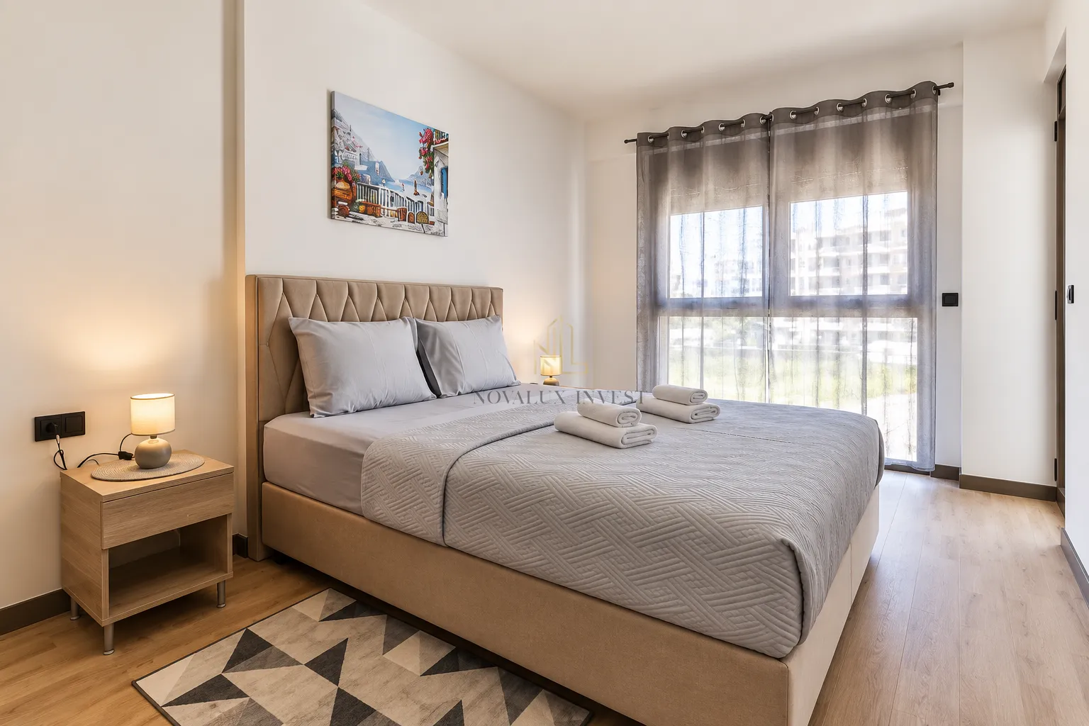 Furnished bedroom with a double bed, bedside table, and window with curtains.
