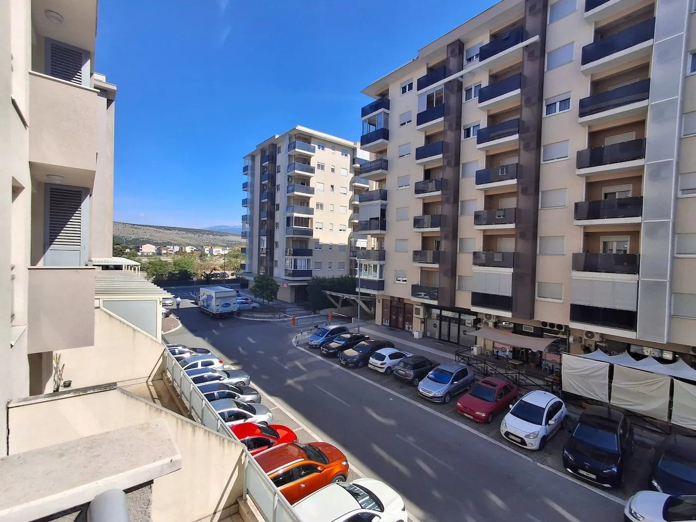 View from the terrace overlooking residential buildings and parking in front.
