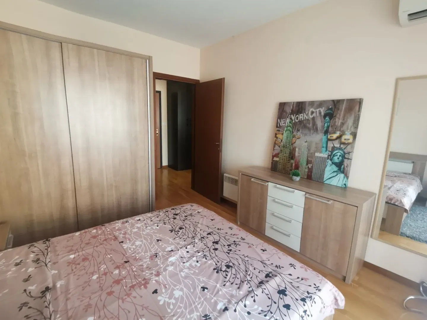 Svijetla spavaća soba sa velikim ormarom i komodom.