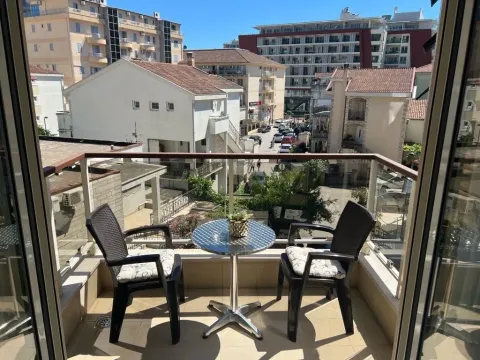 Manji namješteni balkon sa stolom i dvije stolice i pogledom na grad. - image 4