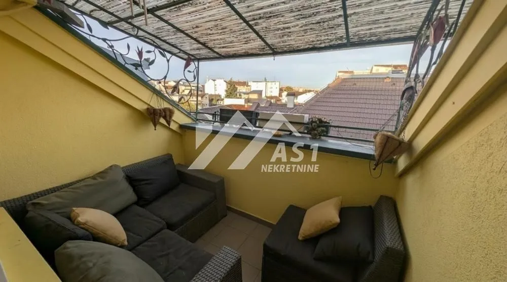 Natkrivena terasa sa garniturom za sedenje i pogledom na grad.