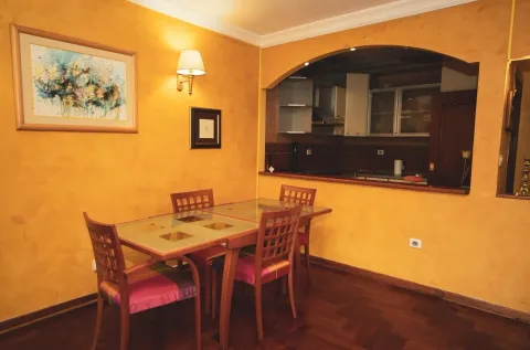 Dining area with a wooden table and chairs, overlooking the kitchen through an archway. - image 3