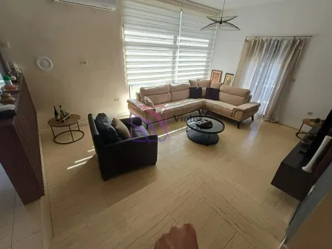 Spacious living room with a sofa set, coffee table, and large windows. - image 9