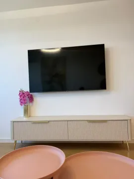 Dnevna soba sa televizorom na zidu i komodom. - image 5