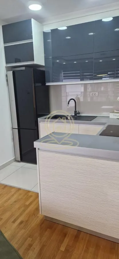 Moderna kuhinja sa ugradnim elementima i frižiderom.