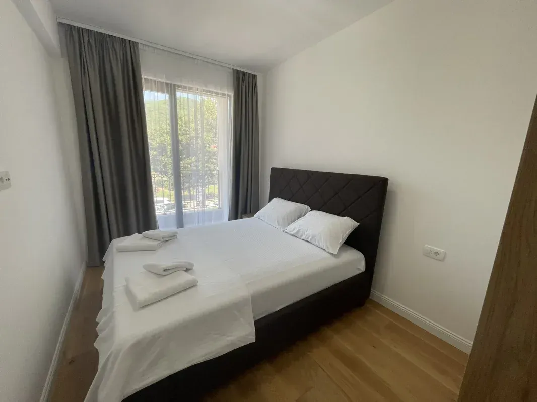 Bright bedroom with a double bed and a window overlooking greenery.