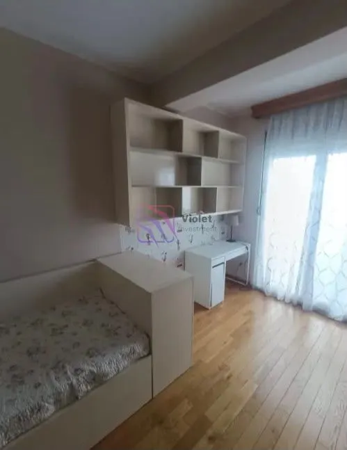 Dječija soba sa krevetom, radnim stolom, policama i parketom na podu.