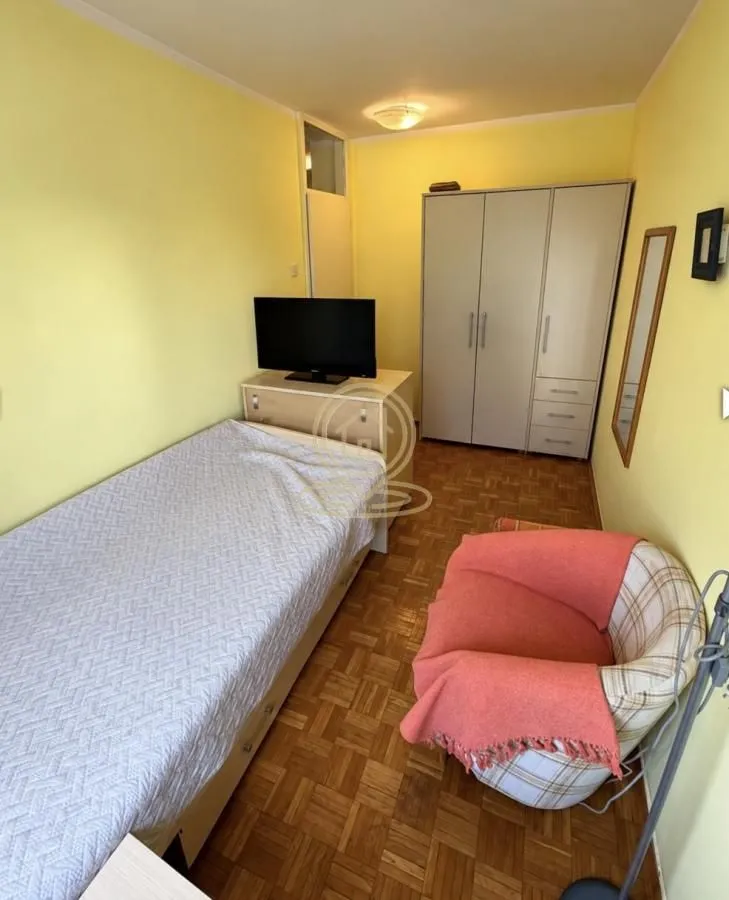 Furnished bedroom with a bed, wardrobe, and an armchair.