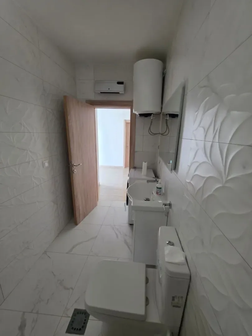 Moderne opremljeno kupatilo sa bijelim keramičkim pločicama i sanitarijama.