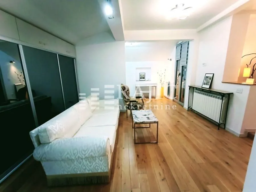 Spacious living room with sofa and wooden floor.