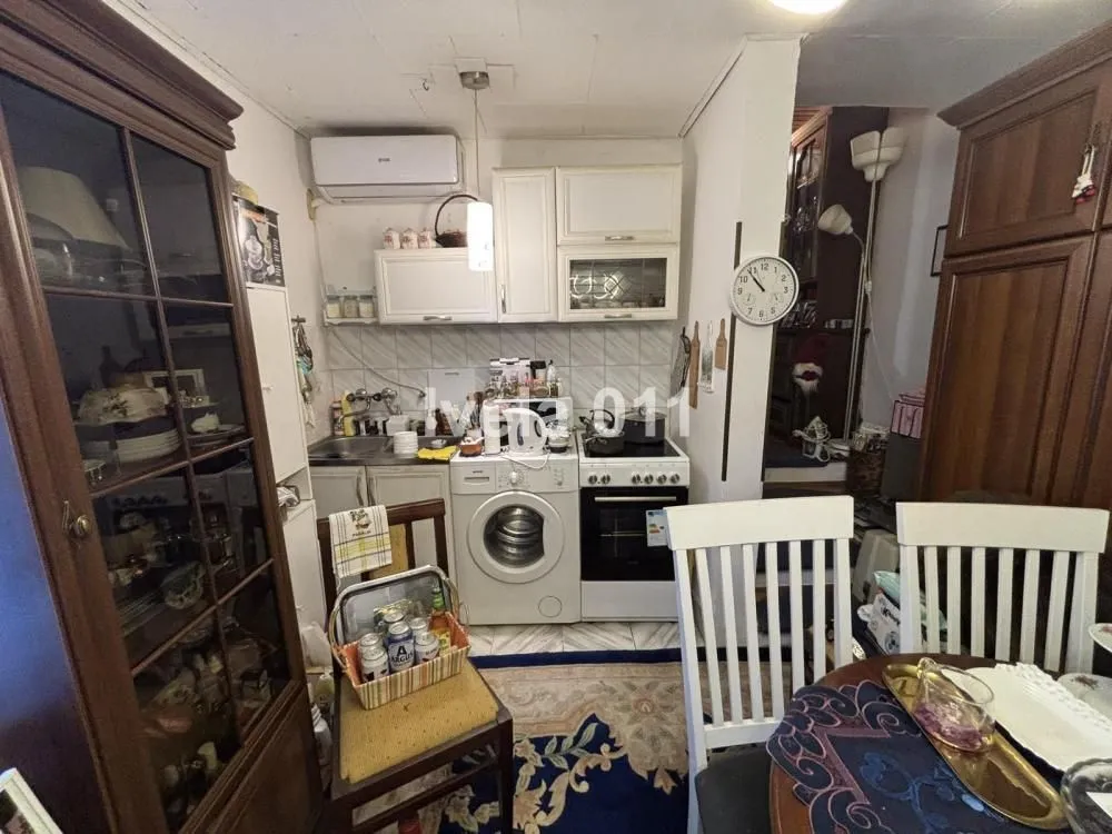Small kitchen with white cabinets, washing machine, and dining table.