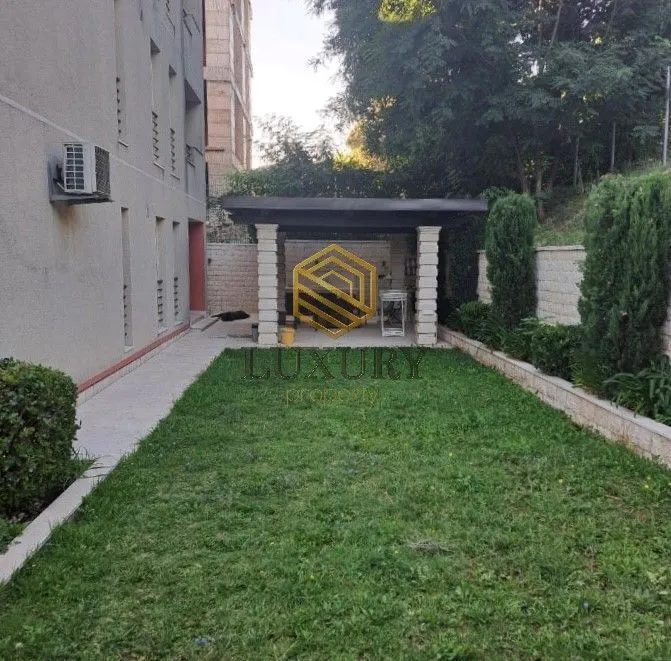 Dvorište zgrade sa travnjakom i natkrivenom terasom.
