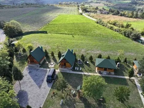 Pogled iz vazduha na drvene kućice u prirodi sa velikim dvorištem i zelenilom. - image 4