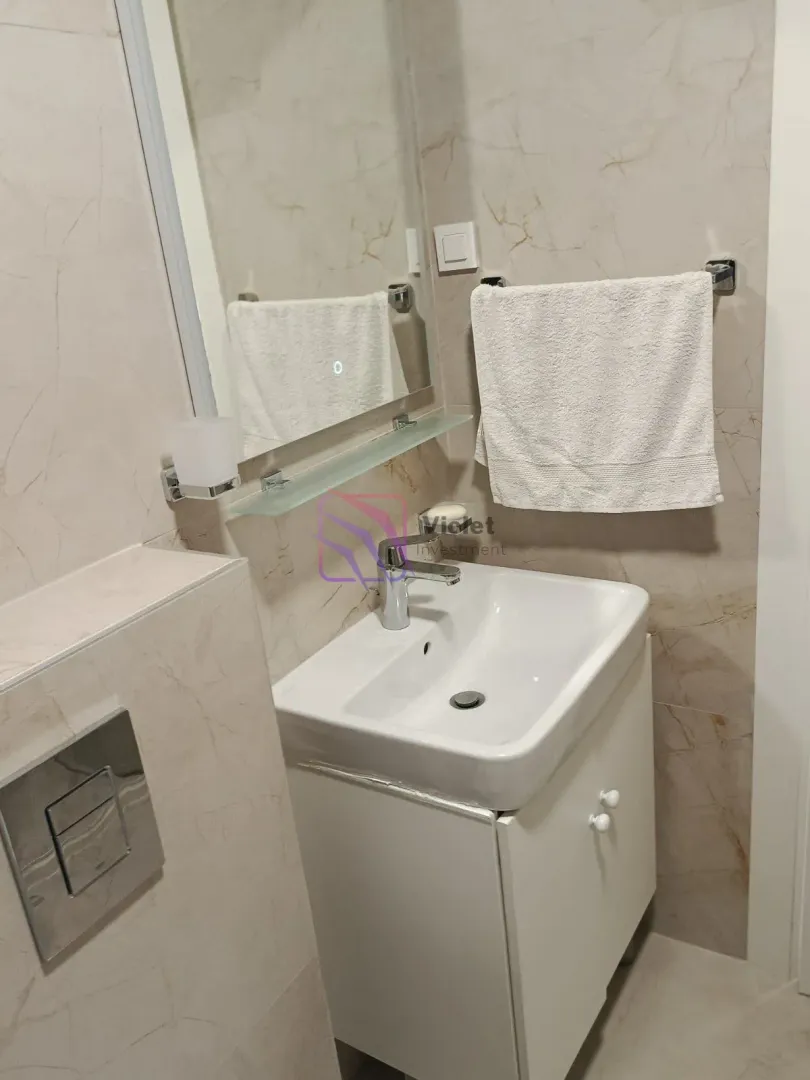 Small bathroom with a washbasin, mirror, and white cabinet.
