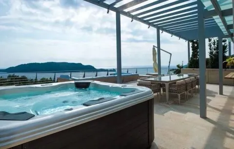 Spacious covered terrace with a jacuzzi, dining table, and sea view. - image 2