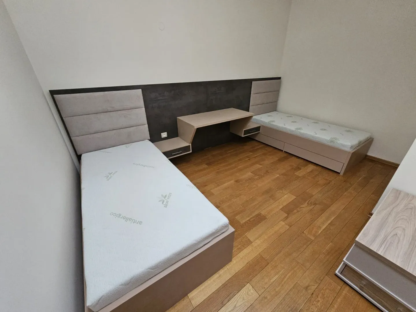 Dječja soba sa dva singl kreveta i radnim stolom između njih.
