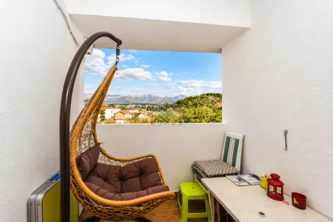 Natkriveni balkon sa visećom foteljom i pogledom na grad i planine. - image 7