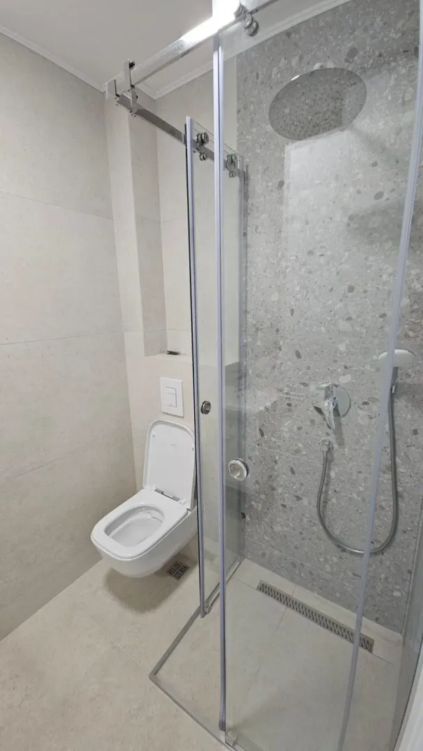 Moderno opremljeno kupatilo sa tuš kabinom i ugradnom šoljom.