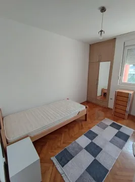 Small bedroom with a bed, wooden wardrobe with a mirror, and parquet flooring. - image 6